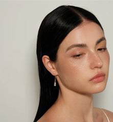 Model wearing Perle Fluide drop earrings, angled portrait