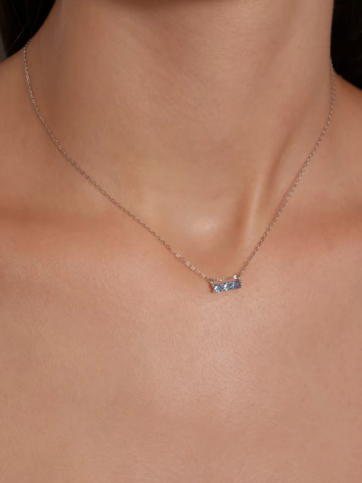 Close-up model view of blue three-stone necklace