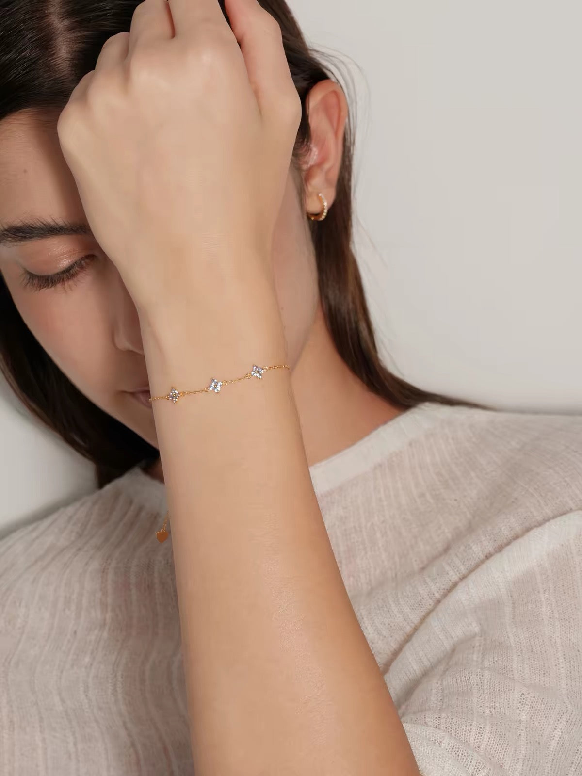 Model wearing gold Clover Bracelet with three pale blue floral stones